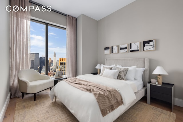 bedroom featuring a view of city, baseboards, and wood finished floors