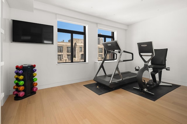 exercise room with baseboards and wood finished floors