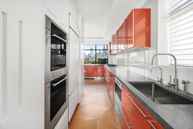 kitchen featuring a view of city, dark countertops, backsplash, stainless steel double oven, and a sink