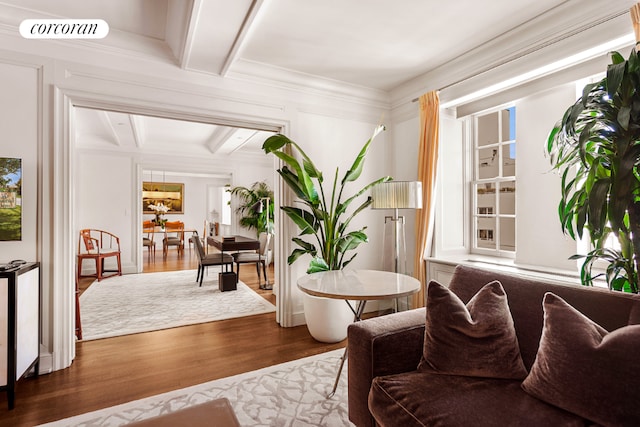 sitting room with hardwood / wood-style floors, ornamental molding, and beamed ceiling