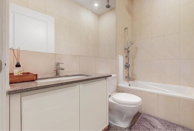 bathroom featuring tile patterned floors, tile walls, a combined bath / shower with rainfall shower, toilet, and vanity