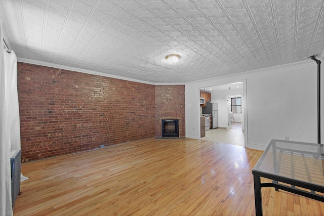 living room with crown molding, brick wall, a fireplace, and light hardwood / wood-style floors