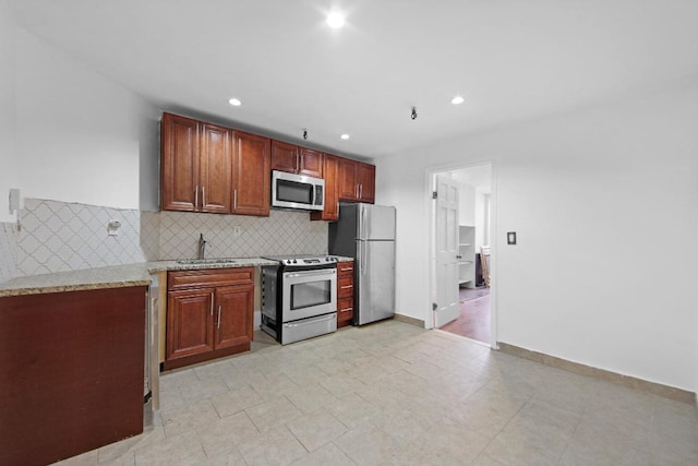 kitchen with sink, backsplash, light stone countertops, and appliances with stainless steel finishes