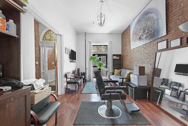 living room featuring hardwood / wood-style flooring, brick wall, and a notable chandelier