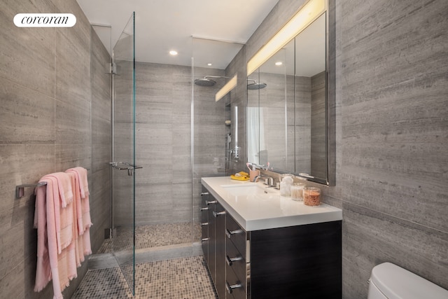 bathroom featuring tile walls, tiled shower, vanity, and toilet