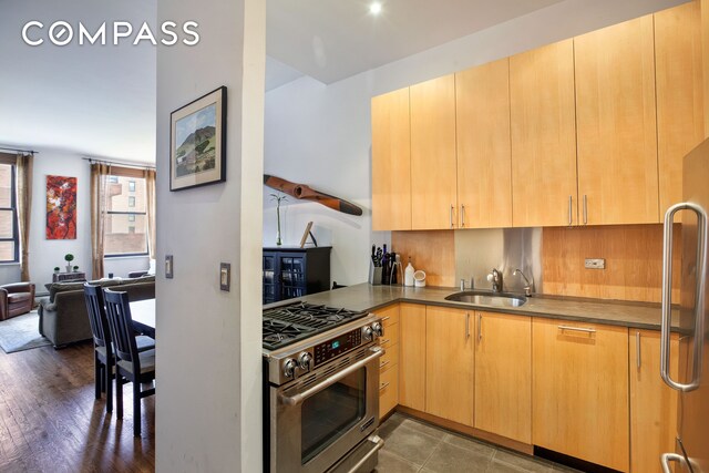 kitchen featuring refrigerator, sink, dark hardwood / wood-style flooring, stainless steel range with gas stovetop, and light brown cabinets