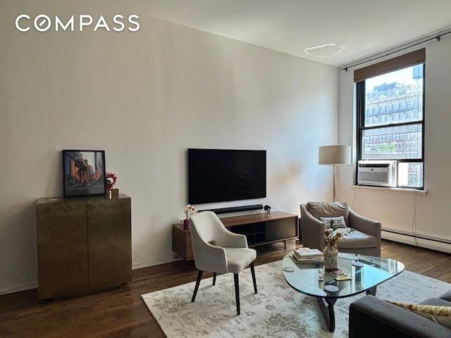 living area with cooling unit, wood finished floors, and a baseboard radiator