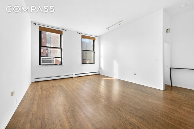 unfurnished room with wood-type flooring, rail lighting, a baseboard heating unit, and cooling unit