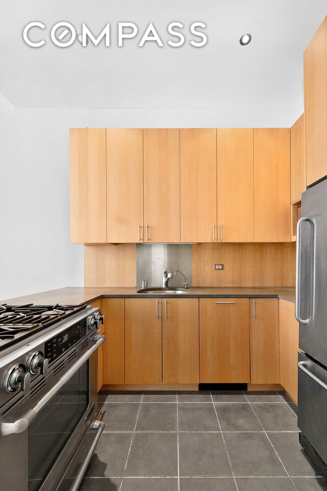 kitchen featuring tasteful backsplash, sink, dark tile patterned floors, and appliances with stainless steel finishes