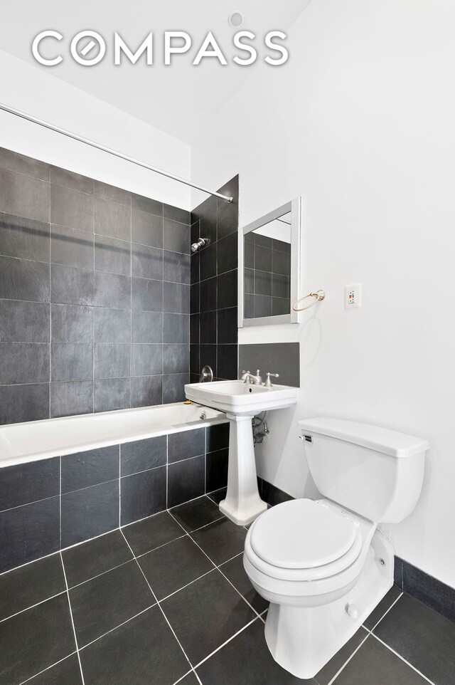 bathroom with tile patterned flooring, toilet, and tiled shower / bath