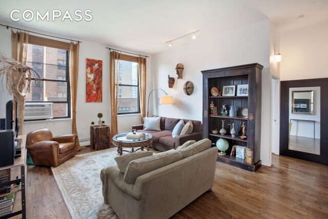 living room with cooling unit, hardwood / wood-style floors, track lighting, and baseboard heating