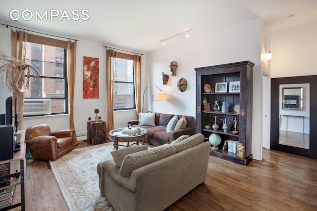 living room featuring cooling unit, track lighting, wood finished floors, and a baseboard heating unit