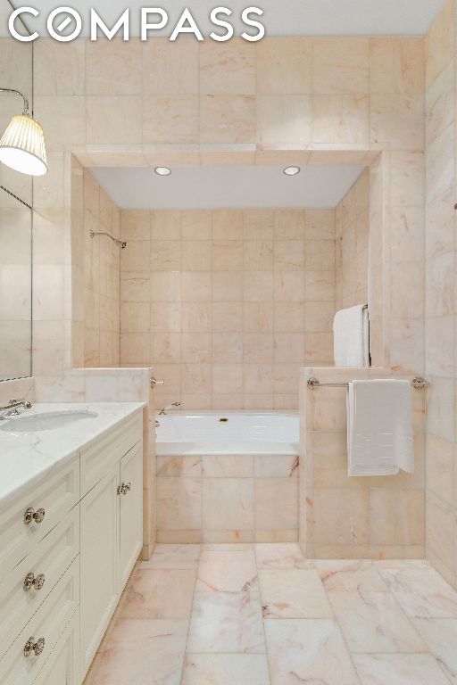 bathroom with vanity, tile walls, and tiled shower / bath