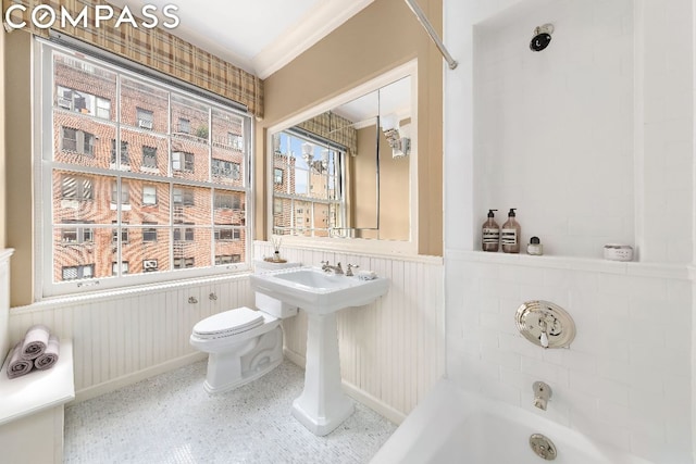 bathroom featuring crown molding, a bathtub, and toilet