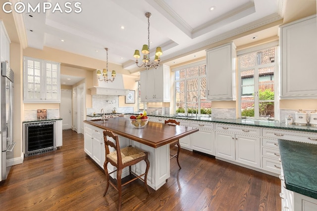 kitchen with white cabinetry, hanging light fixtures, dark wood-type flooring, and beverage cooler