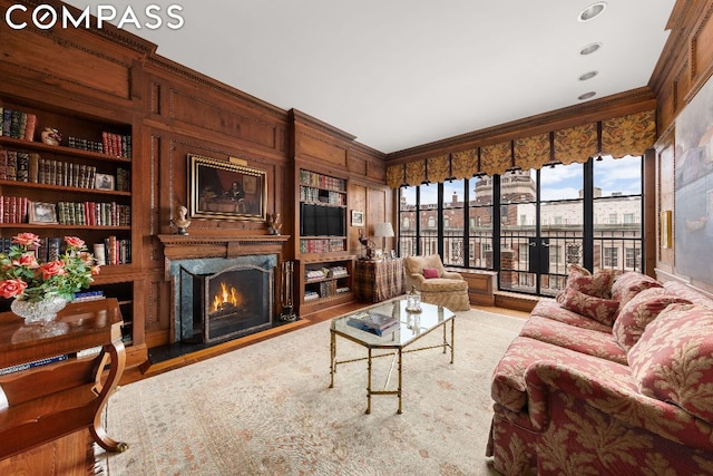 living room featuring crown molding, a fireplace, and built in shelves