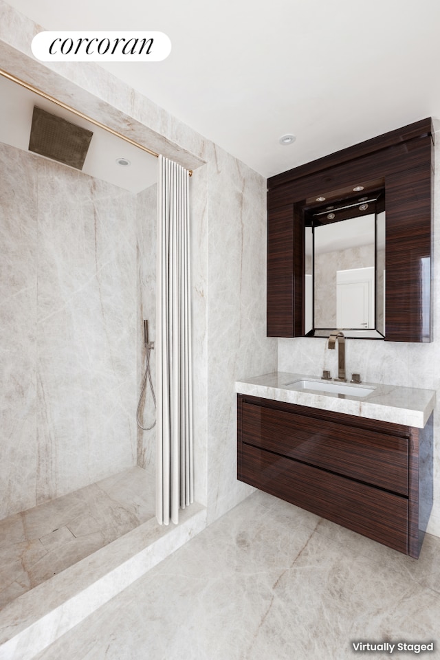 full bathroom with a walk in shower, vanity, and tile walls