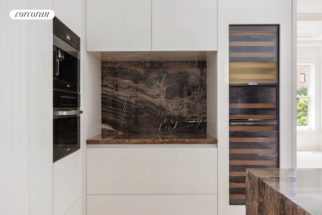 kitchen featuring wall oven, modern cabinets, dark stone counters, and white cabinets