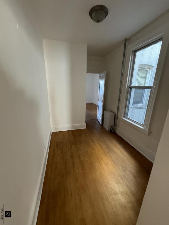 corridor featuring radiator, baseboards, and dark wood-type flooring