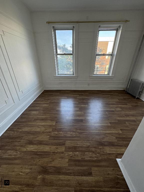 spare room featuring dark wood-type flooring, visible vents, and baseboards