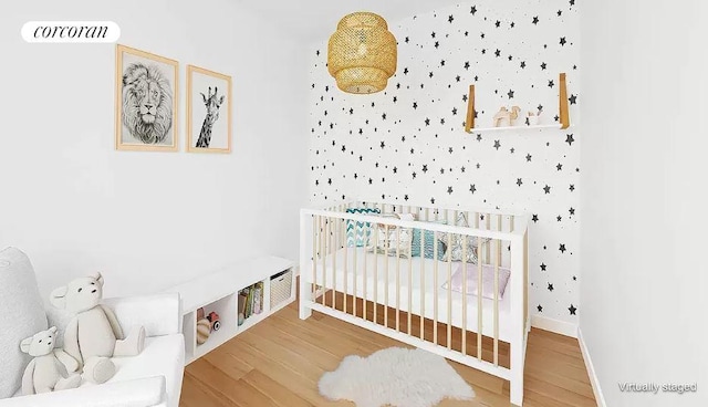 bedroom with a nursery area and hardwood / wood-style flooring