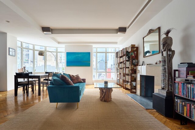 interior space featuring light parquet floors, a tiled fireplace, and a wall of windows