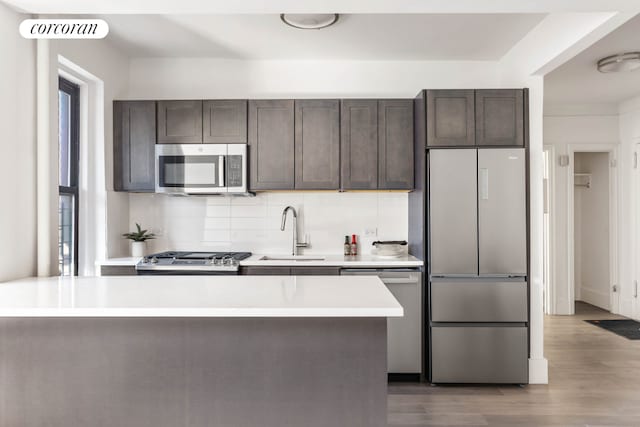 kitchen featuring stainless steel appliances, backsplash, dark brown cabinetry, and sink