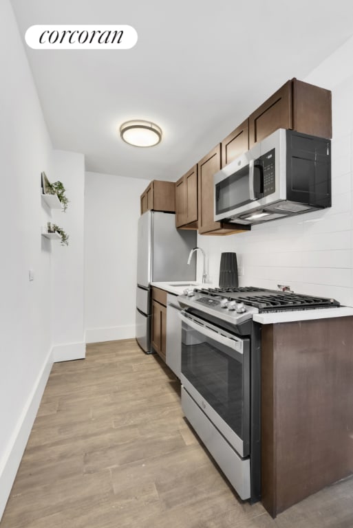 kitchen with stainless steel appliances, sink, and light wood-type flooring