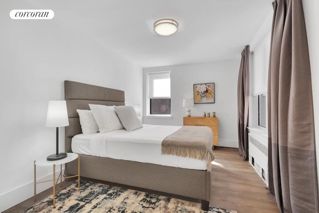 bedroom featuring radiator heating unit and light hardwood / wood-style floors