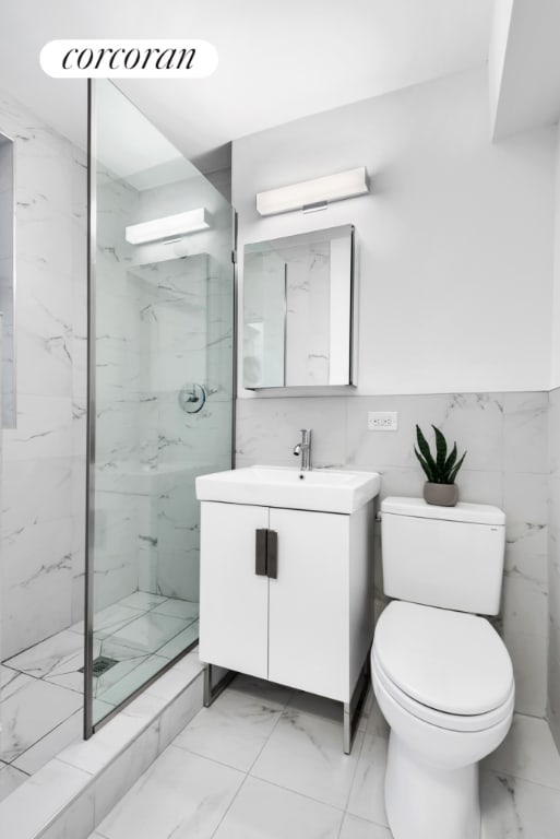 bathroom featuring tile walls, toilet, a tile shower, and vanity