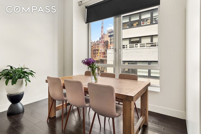 dining space featuring dark wood-type flooring, a view of city, and baseboards