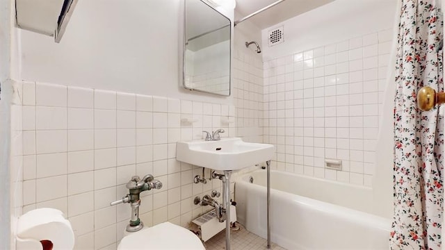 full bathroom with tile walls, shower / bath combo, tile patterned floors, and toilet