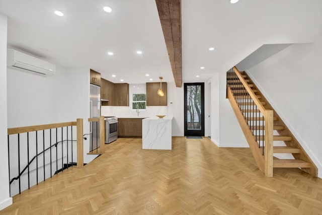 kitchen with light parquet floors, an AC wall unit, sink, and appliances with stainless steel finishes