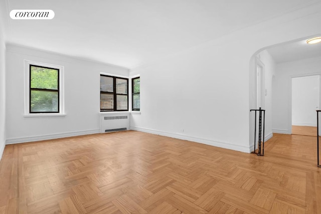 unfurnished room with light parquet flooring, radiator, and a wealth of natural light