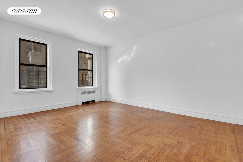 unfurnished room featuring radiator and light parquet floors