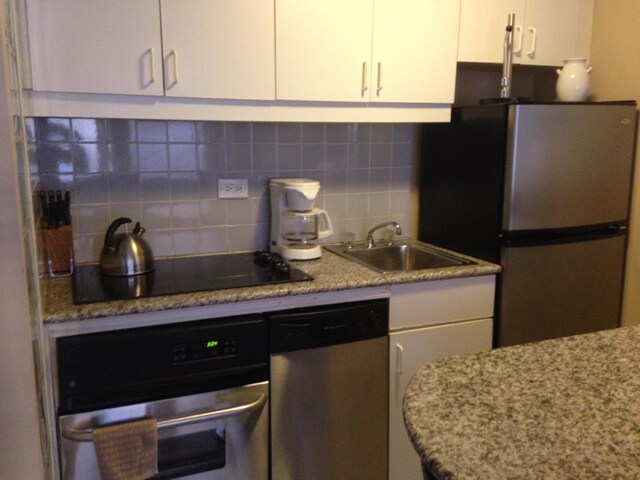 kitchen with backsplash, stainless steel appliances, sink, and white cabinets