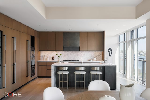 555 W 22nd St Unit Ph16Be, New York City, NY 10011 - kitchen featuring range hood, decorative backsplash, light countertops, a breakfast bar, and recessed lighting