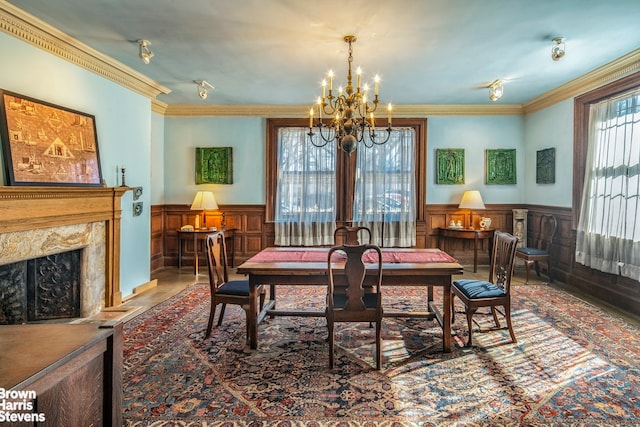 dining area featuring a premium fireplace, crown molding, and a notable chandelier