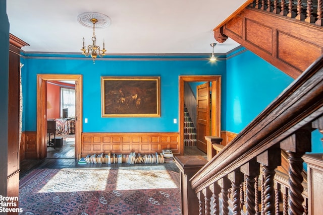 hallway featuring dark hardwood / wood-style flooring, crown molding, and a chandelier