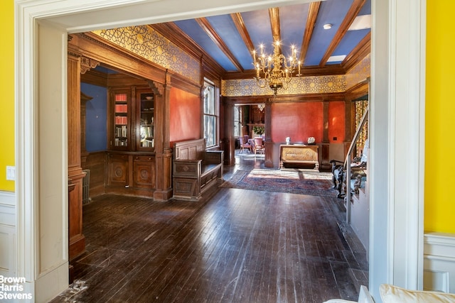 foyer entrance with ornamental molding, dark hardwood / wood-style flooring, beam ceiling, and a chandelier