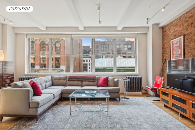 living room with brick wall, radiator heating unit, visible vents, and rail lighting