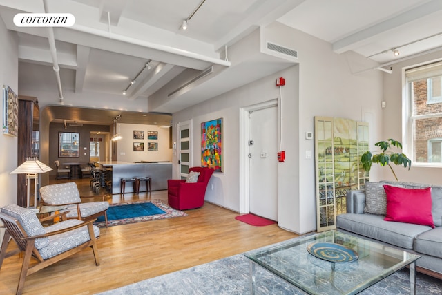 living room with hardwood / wood-style flooring, rail lighting, and beamed ceiling