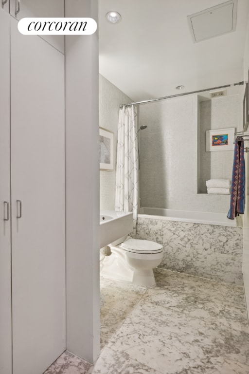 bathroom featuring shower / bathtub combination with curtain and toilet