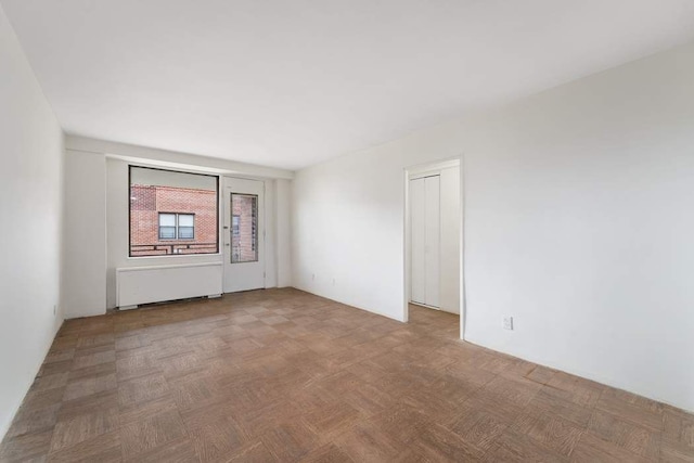 empty room with radiator heating unit and parquet floors