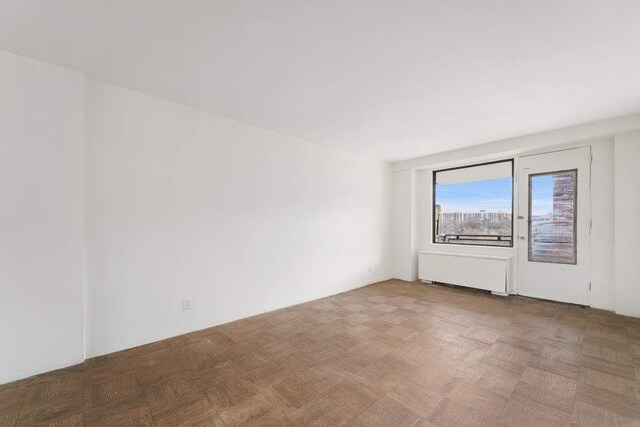 spare room with radiator and light parquet floors