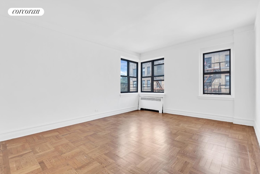 spare room featuring baseboards, visible vents, and radiator heating unit