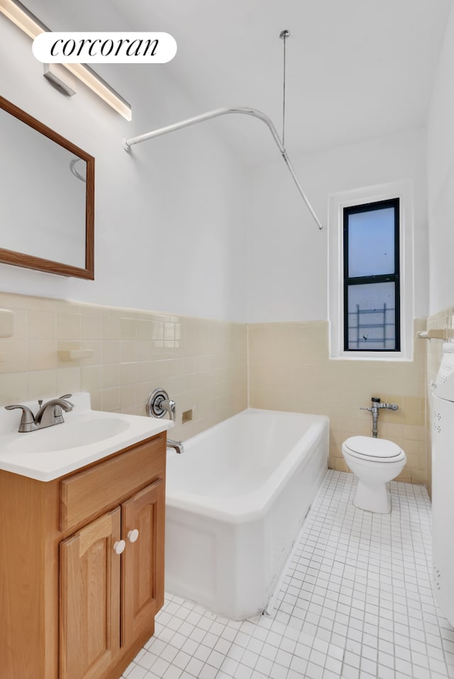 bathroom with a tub to relax in, toilet, tile patterned flooring, vanity, and tile walls