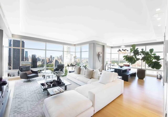 living room featuring floor to ceiling windows, a city view, a raised ceiling, wood finished floors, and a chandelier