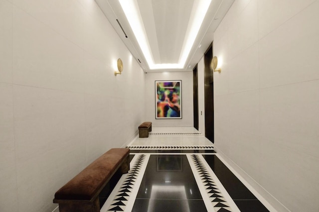 hall featuring tile walls and baseboards