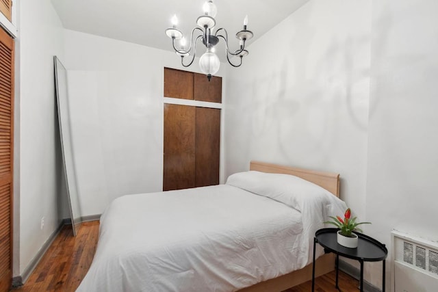 bedroom featuring radiator heating unit, a closet, dark hardwood / wood-style flooring, and an inviting chandelier